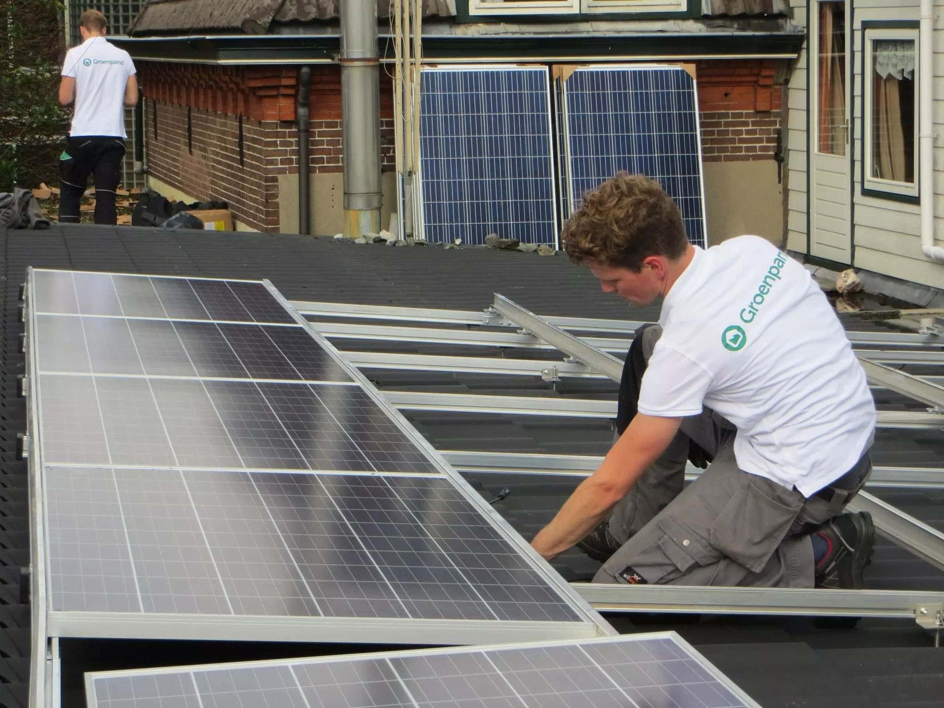 groenpand monteurs bezig met installatie zonnepanelen op licht hellend dak