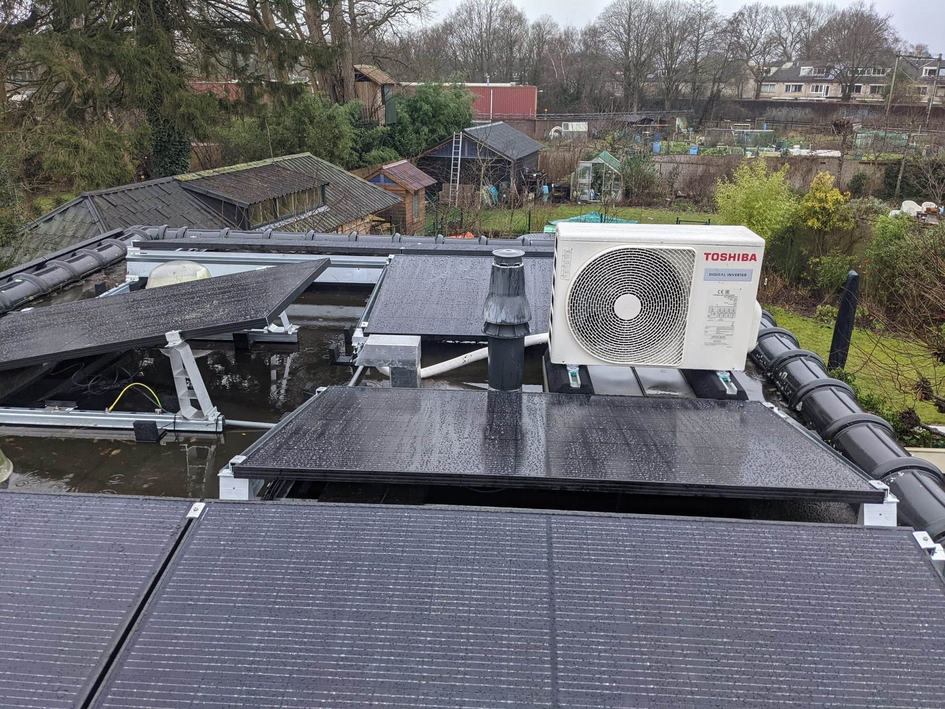 zonnepanelen en warmtepomp buitenunit op dak van woning