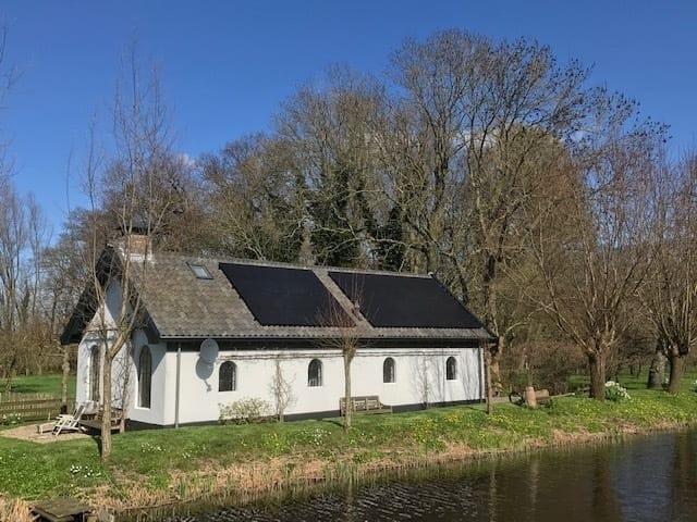 zonnepanelen op dak van karakteristieke vrijstaande woning naast het water