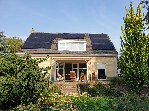 huis met zonnepanelen dak omringt door groene tuin