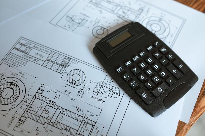 bouwplannen van een woning met een rekenmachine