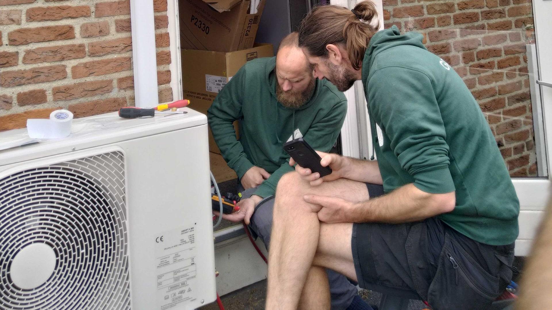 twee groenpand monteurs controleren een warmtepomp buitenunit