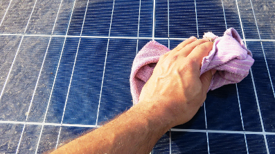 monteur reinigt een zonnepaneel met een doekje